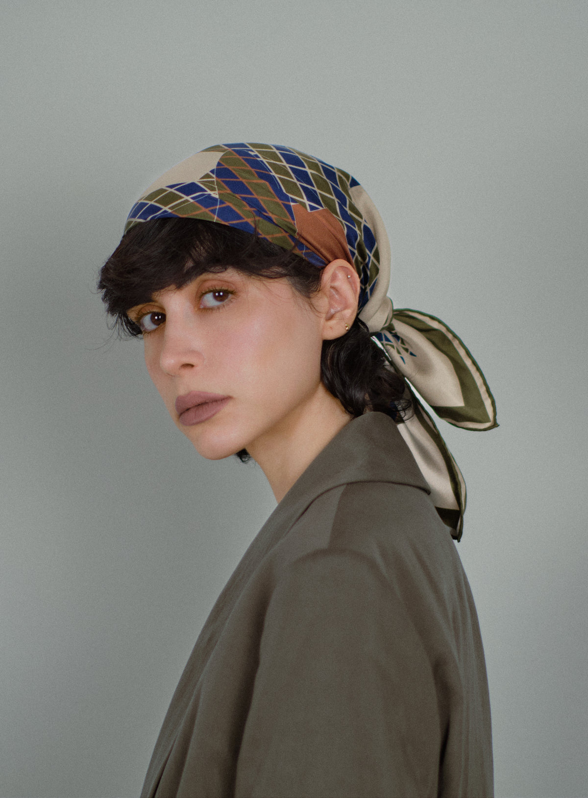 The Crossing silk carré worn as a headscarf, tied at the nape