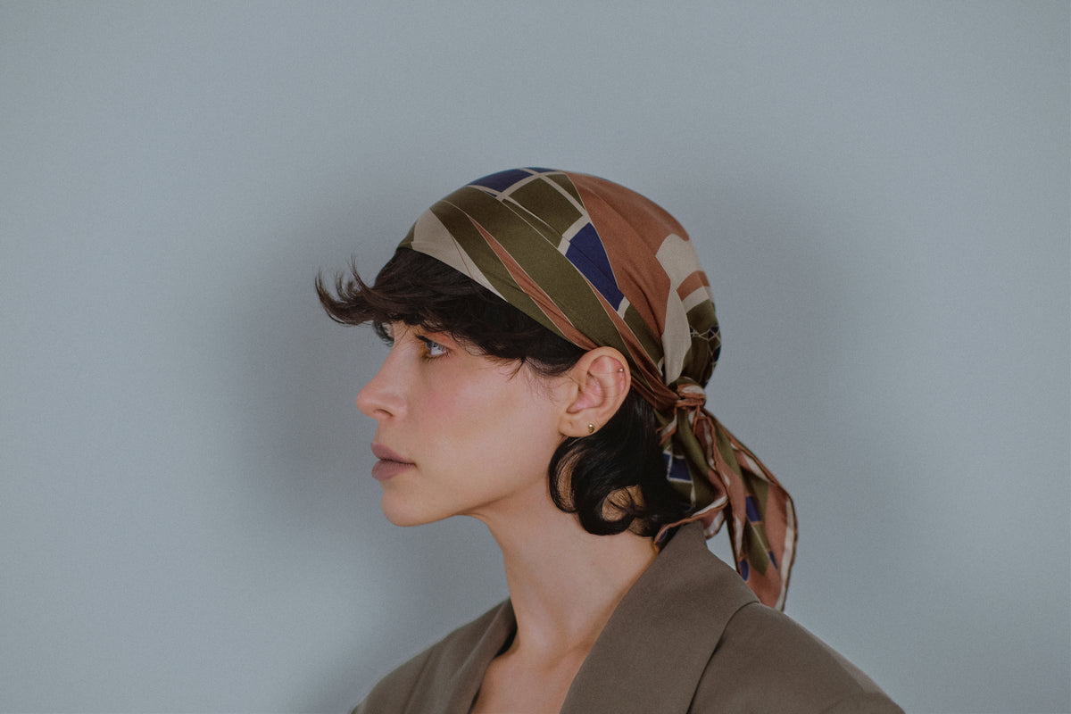 The Graft silk carré tied over the hair, in profile, with the ends falling at the nape