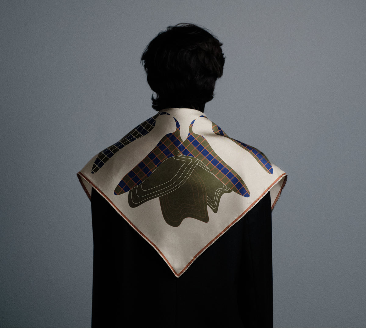 The Quatrefoil silk carré worn over the shoulders, seen from behind — the full motif opened out